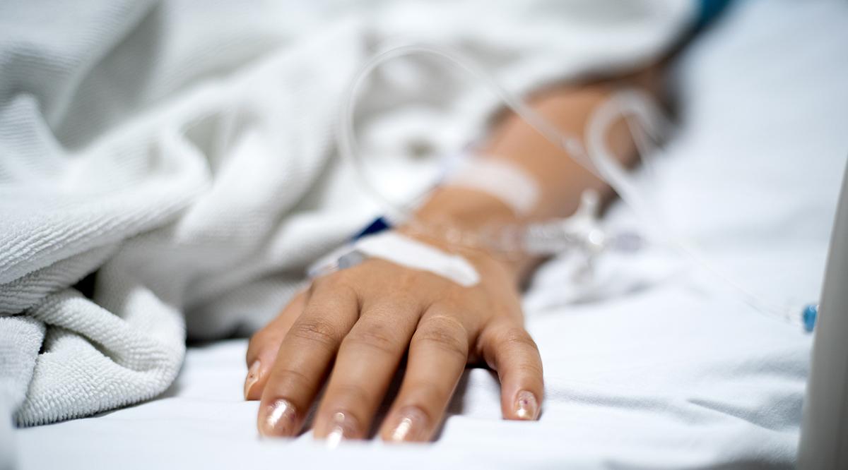 Girl patient with IV drip medicine attached in hospital.